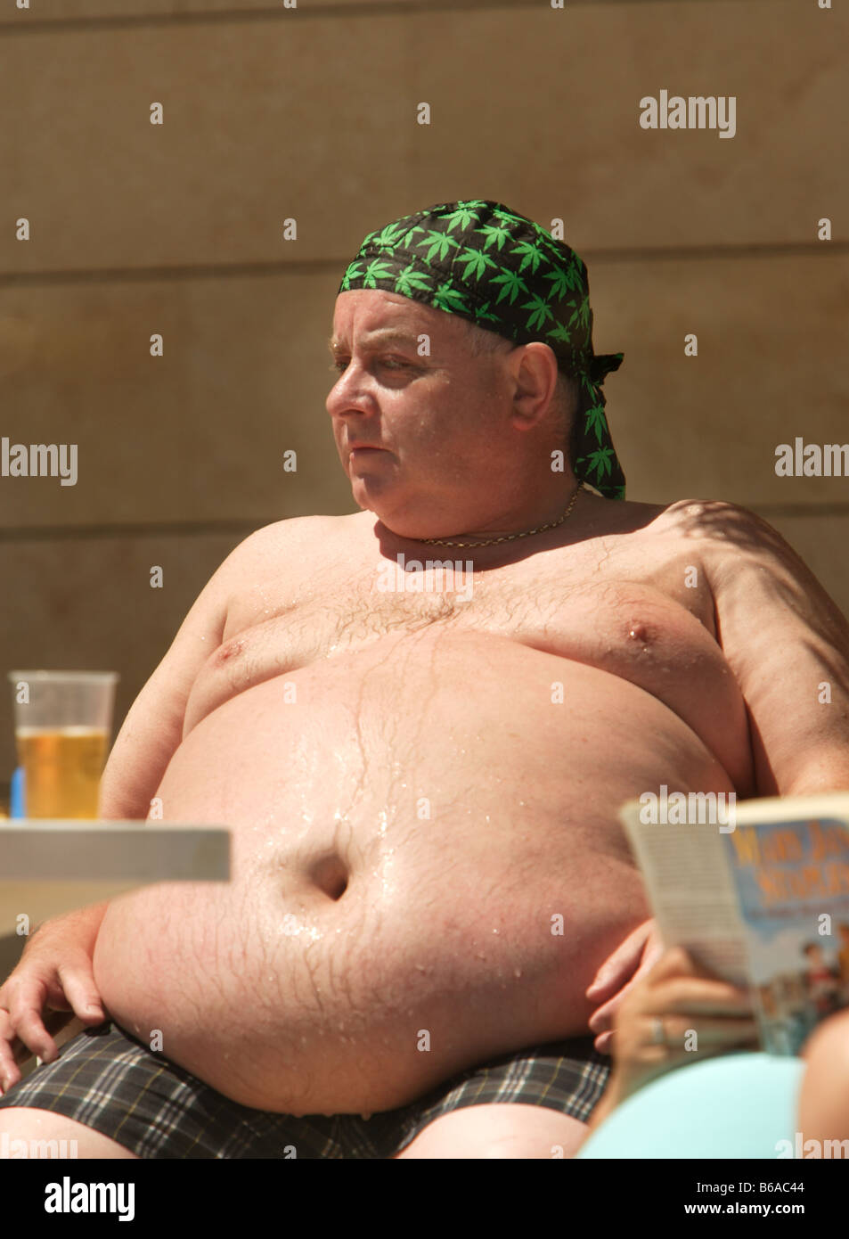 Fat man with huge fat belly and deep belly button sweating while sitting in  the sun Stock Photo - Alamy