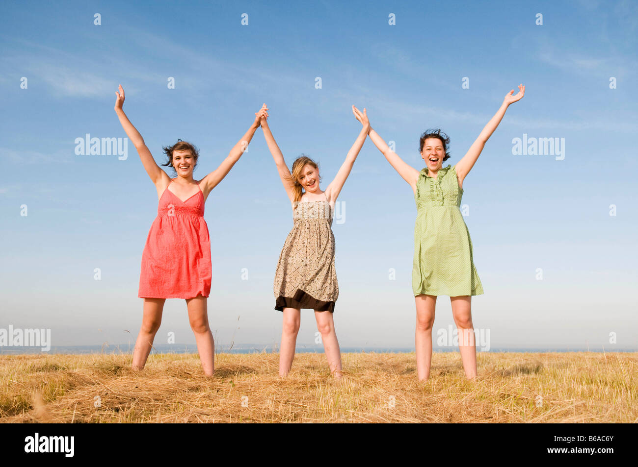 Three teenage girls hold hands up high Stock Photo - Alamy