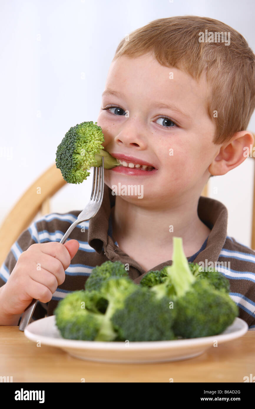 Young boy eating plate of broccoli Stock Photo