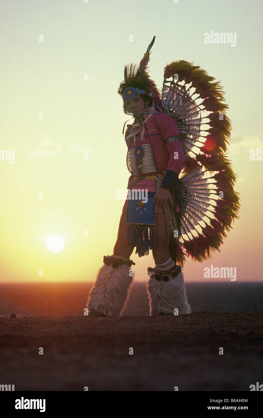 A young Comanche Indian dancer at sunset wearing eagle feathers in his costume Stock Photo