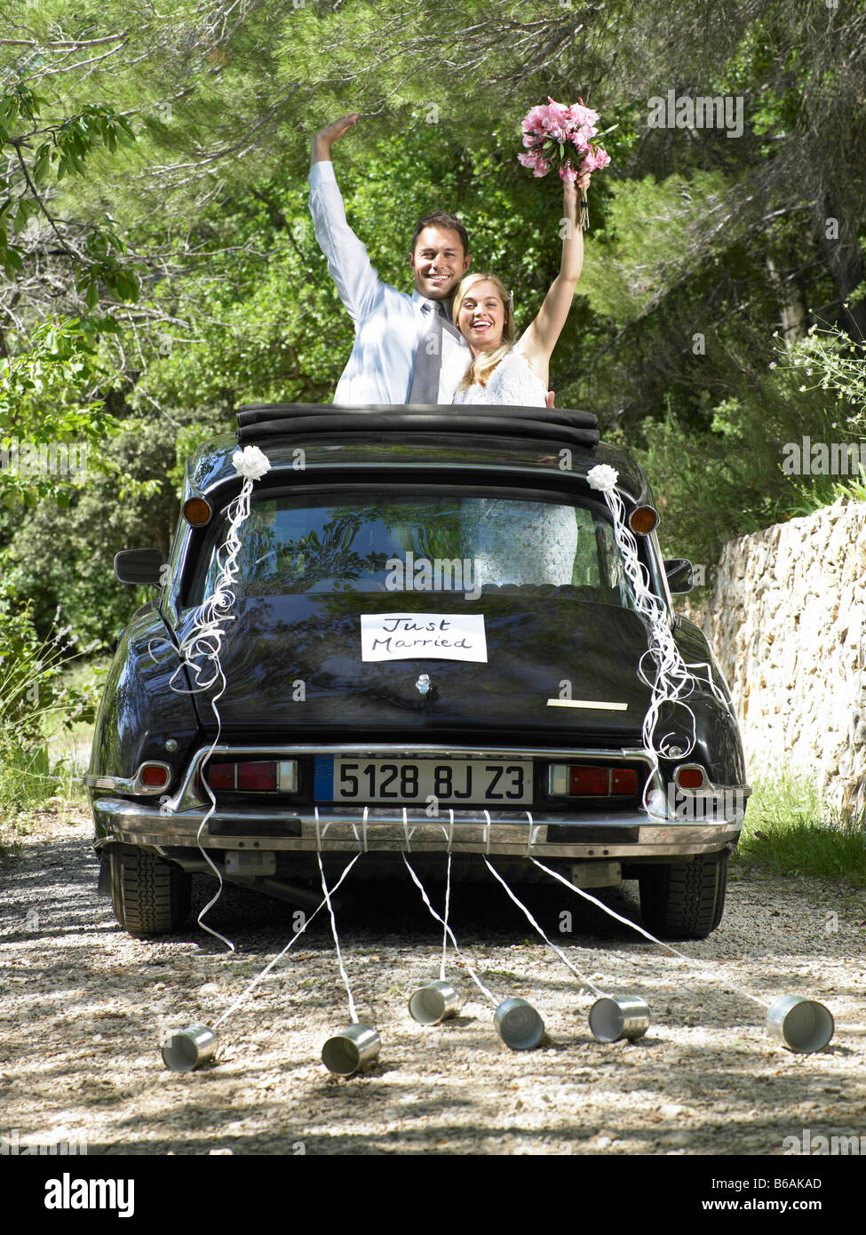 Bride and groom waving from wedding car Stock Photo - Alamy