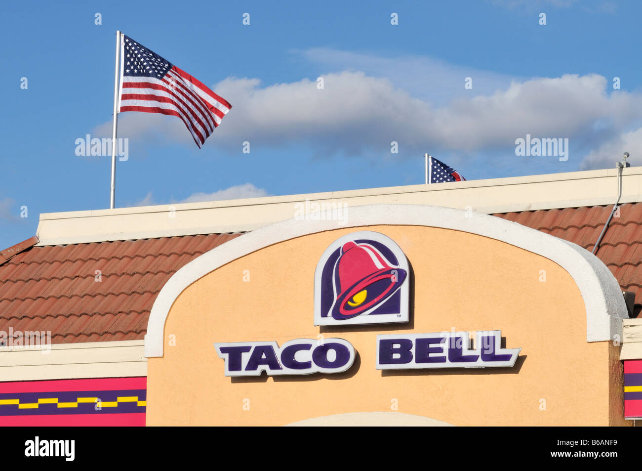 Taco Bell Logo and sign on the exterior of restaurant  with american flag on pole in background. Stock Photo