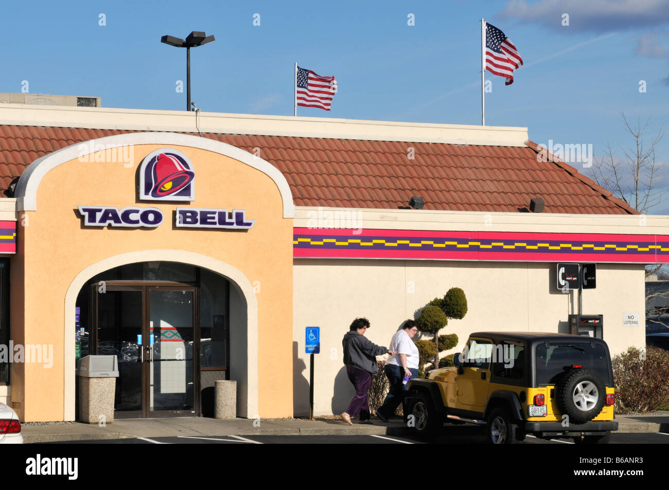 Exterior and entry  of Taco Bell restaurant with 2 people walking to car. USA Stock Photo