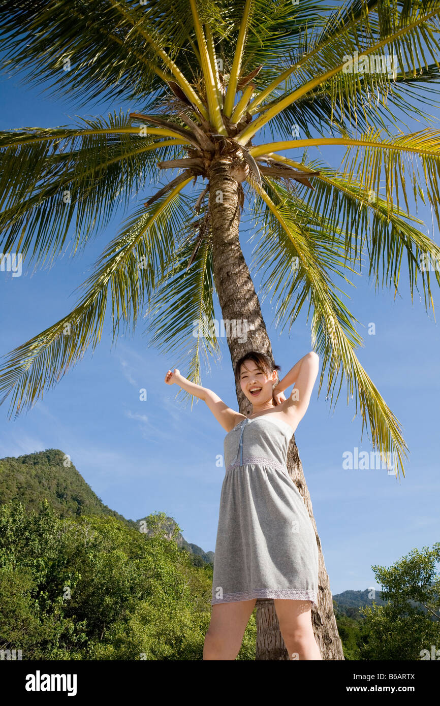 Young woman standing in front of palm tree Stock Photo - Alamy