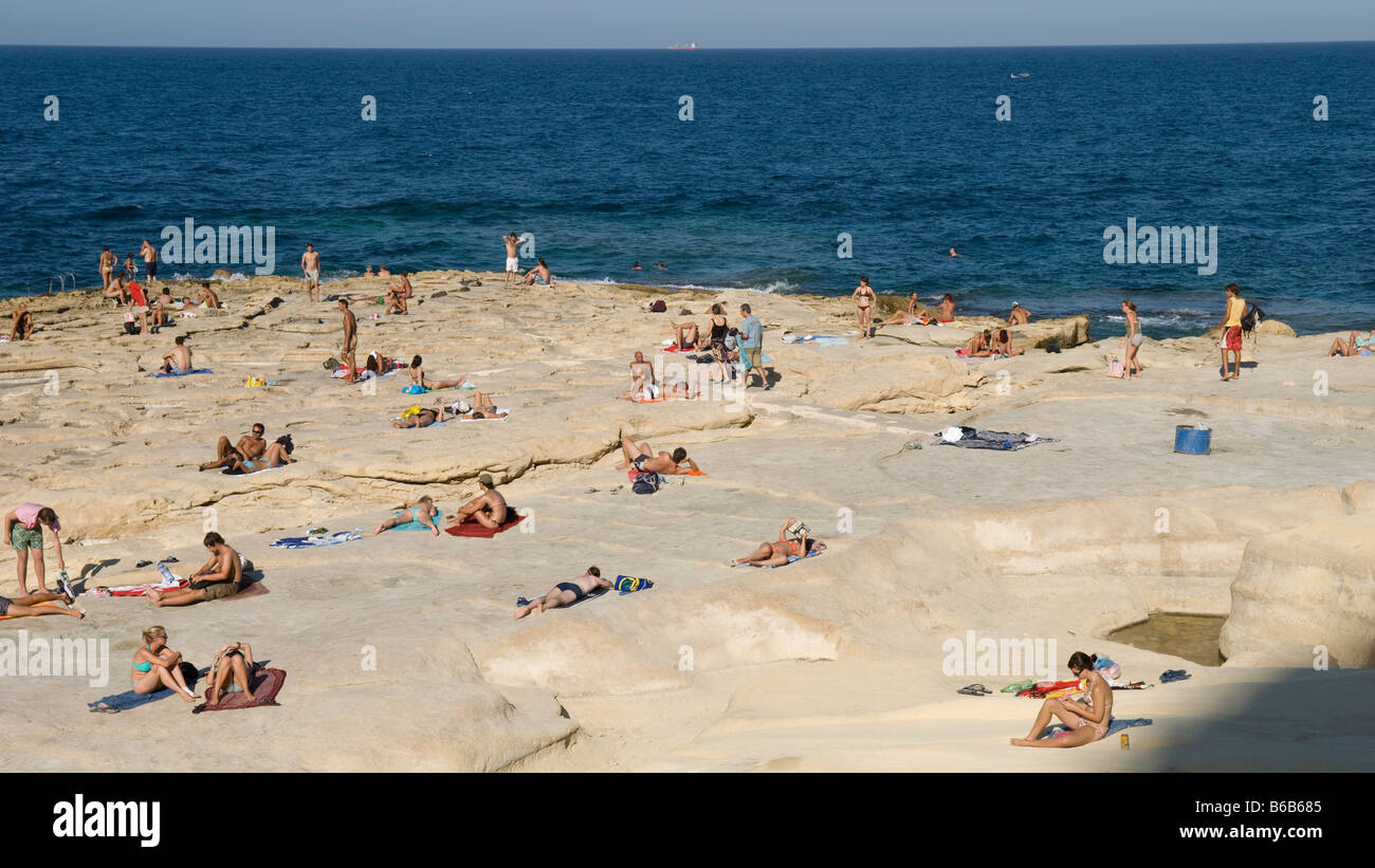 Sunbathing people on rocky beach, Sliema Malta Stock Photo