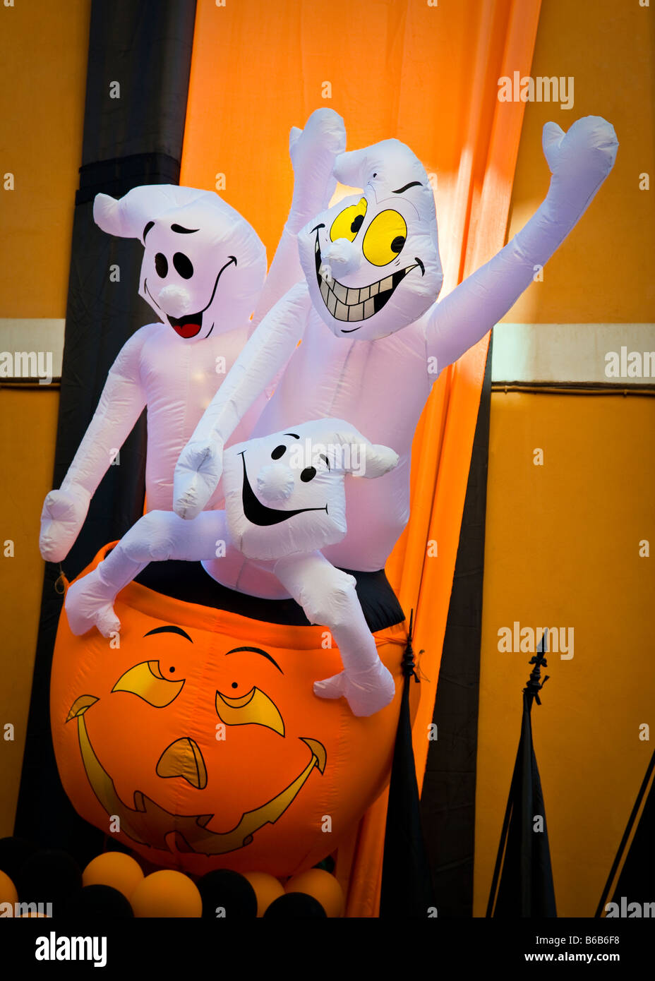 Inflatable smiling ghosts sitting in a fake pumpkin in a Halloween display in Italy Stock Photo