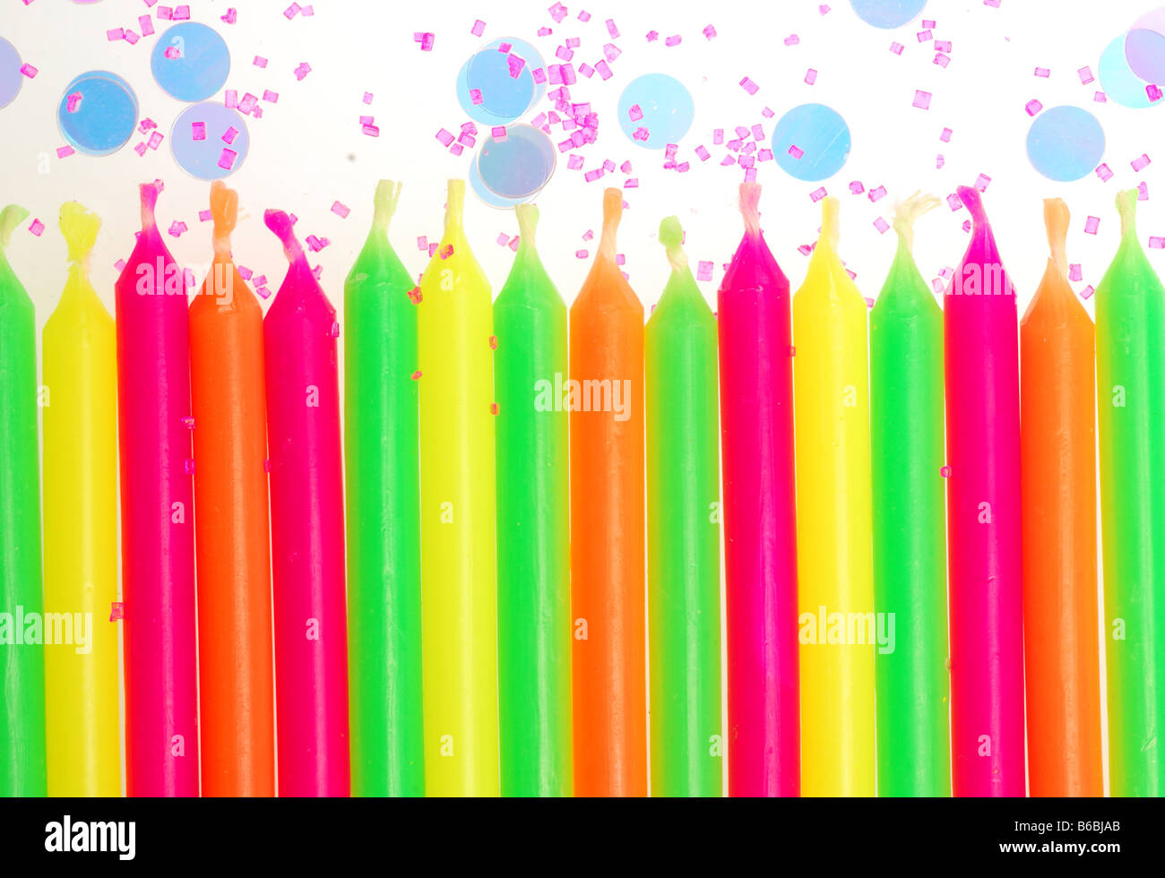 Row of unlit birthday candles with confetti and cake sprinkles Stock