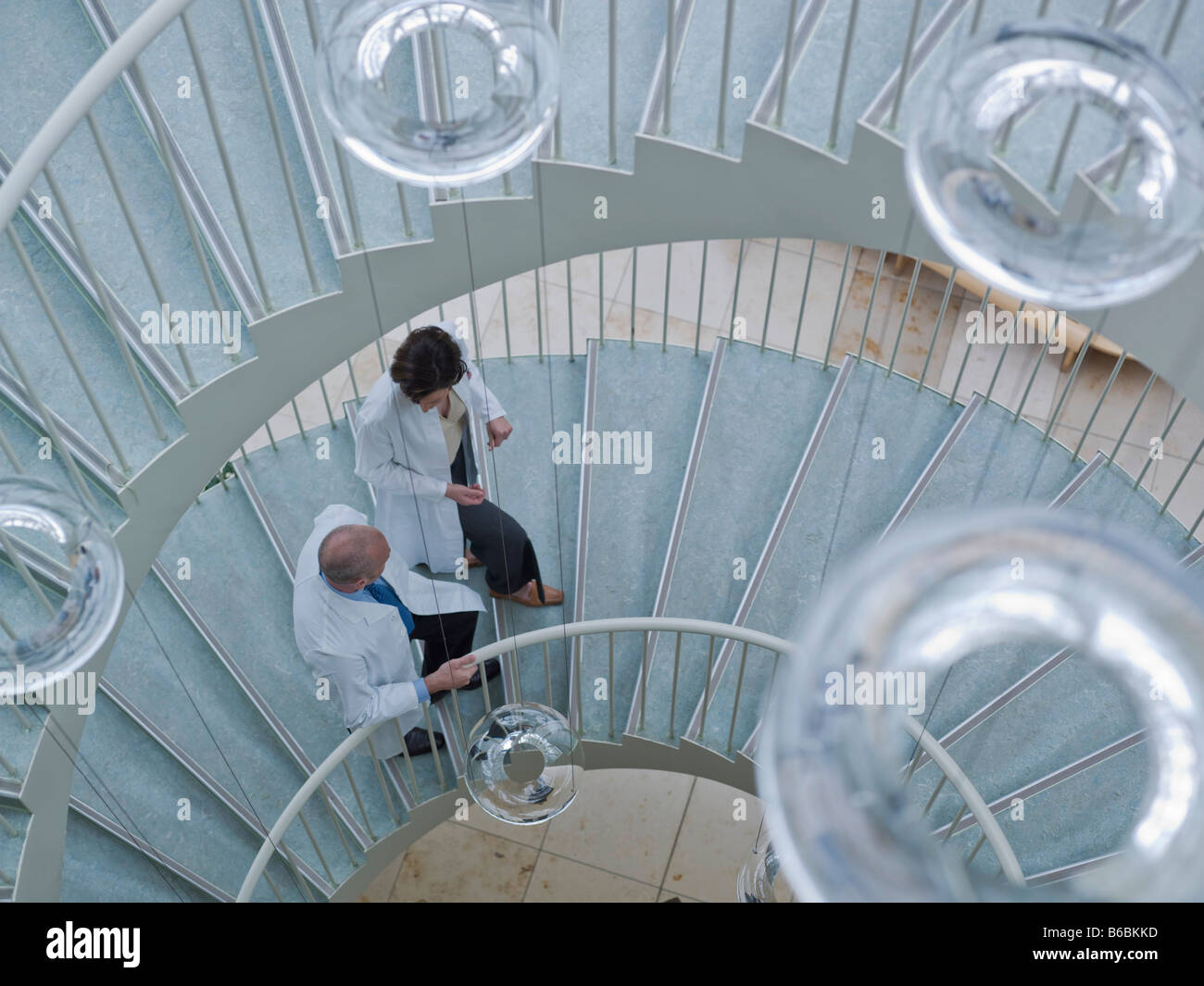 Doctors moving up on spiral staircase Stock Photo