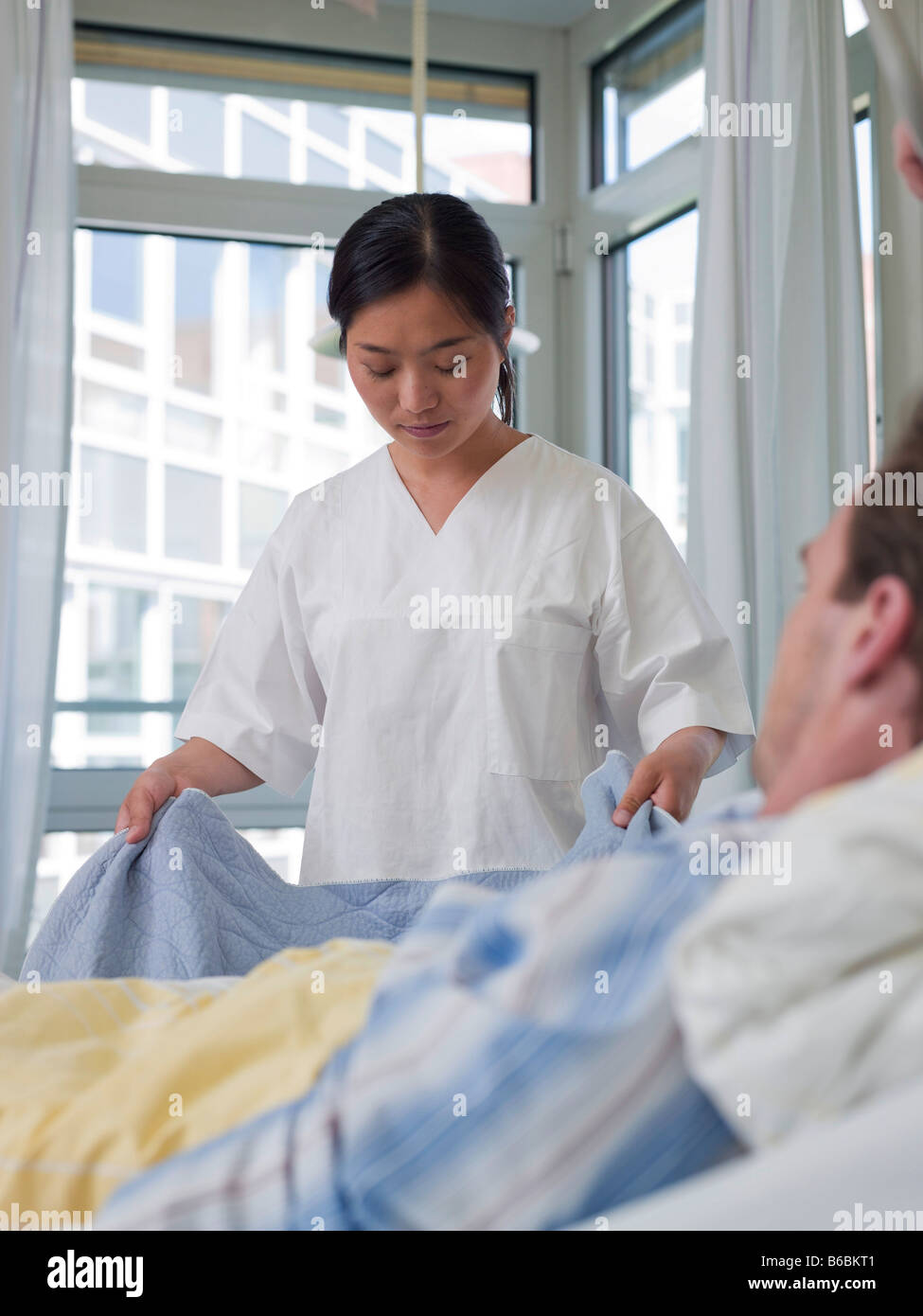 Female nurse changing bed sheet of patient's bed Stock Photo Alamy