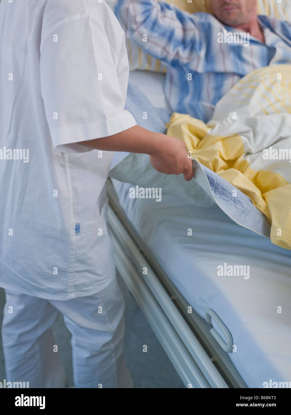 Female nurse changing bed sheet of patient's bed Stock Photo Alamy