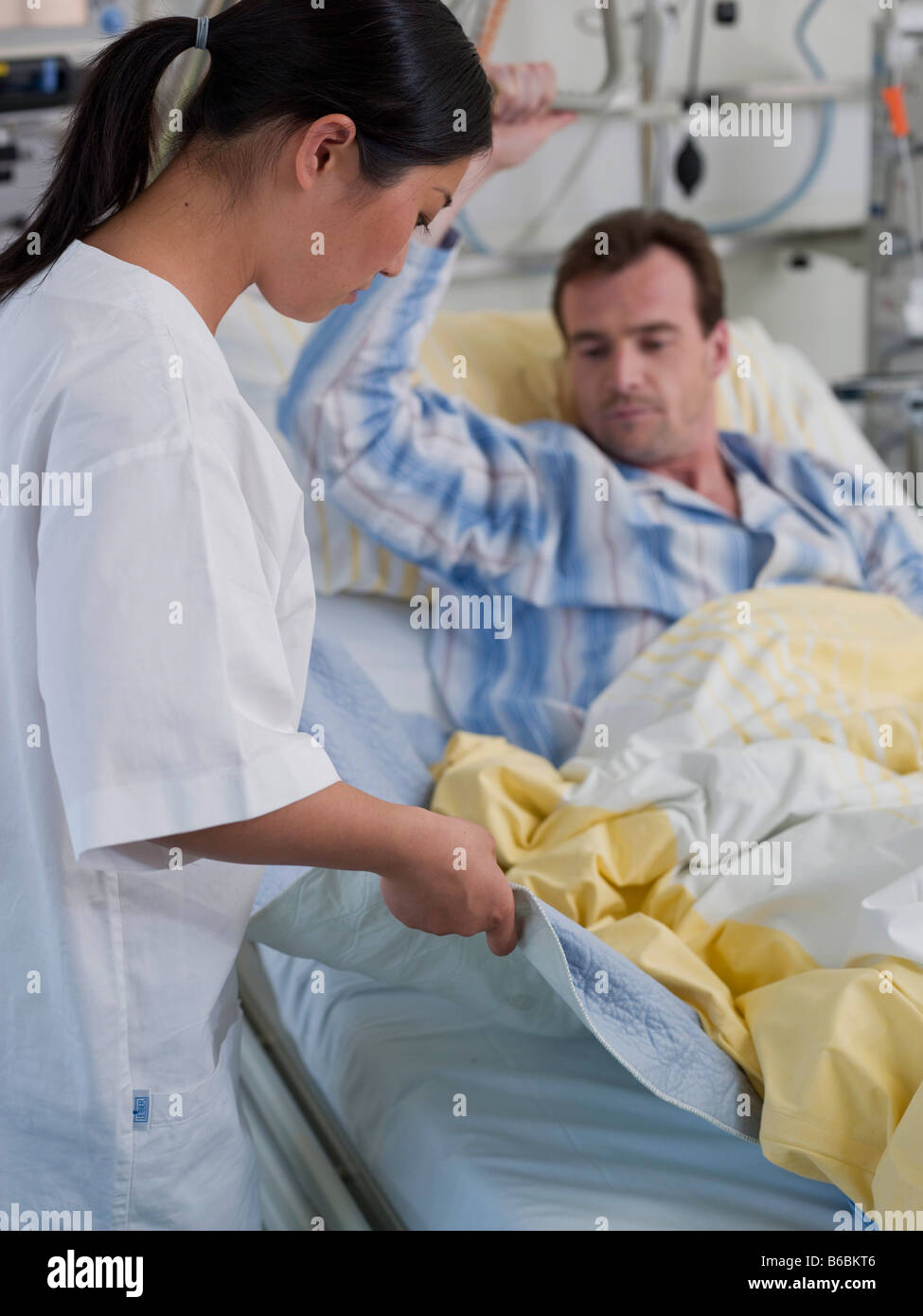 Female nurse changing bed sheet of patient's bed Stock Photo Alamy