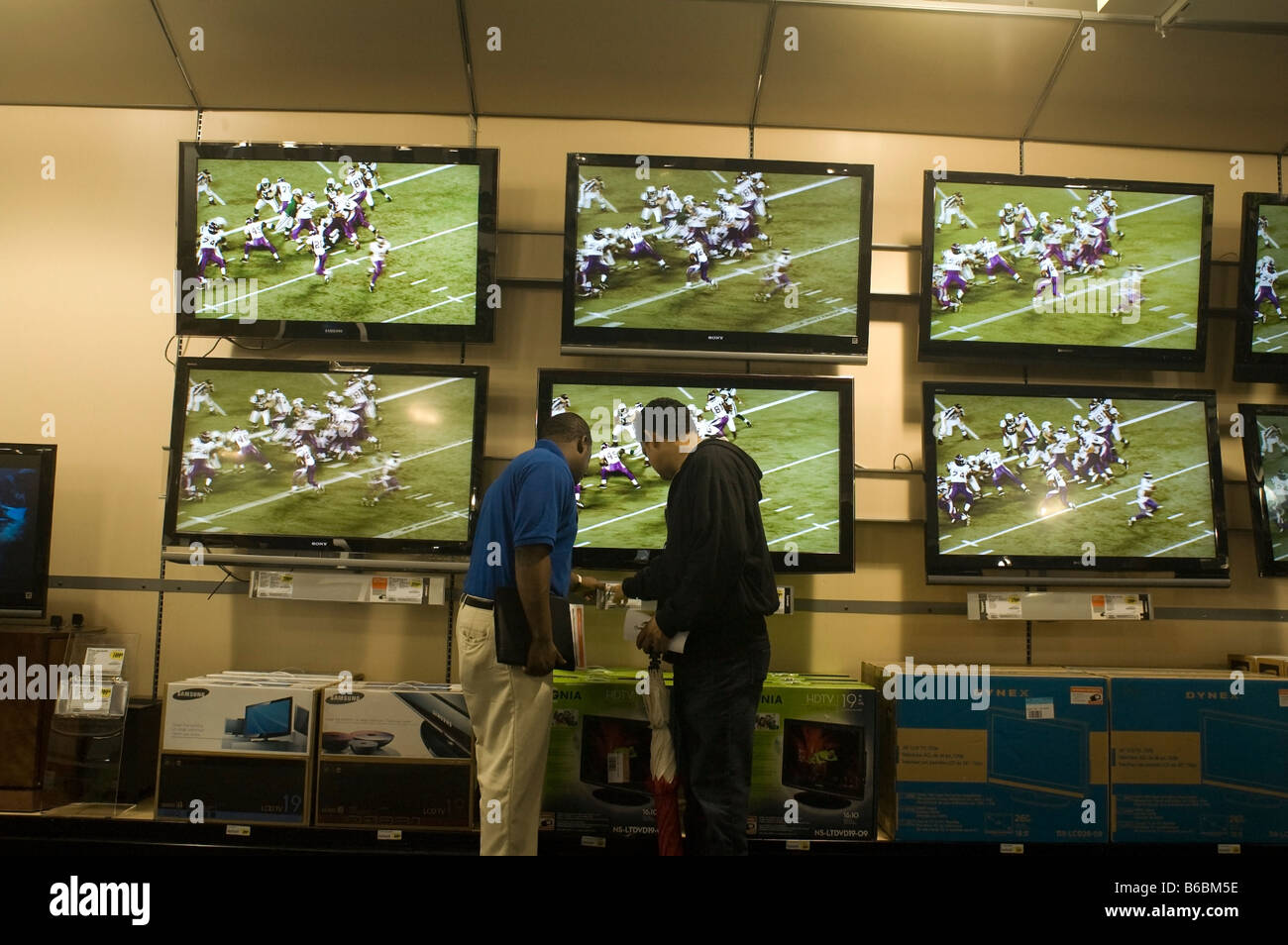 A sales associate assists a customer with flat screen televisions at the grand opening of a Best Buy electronic store Stock Photo