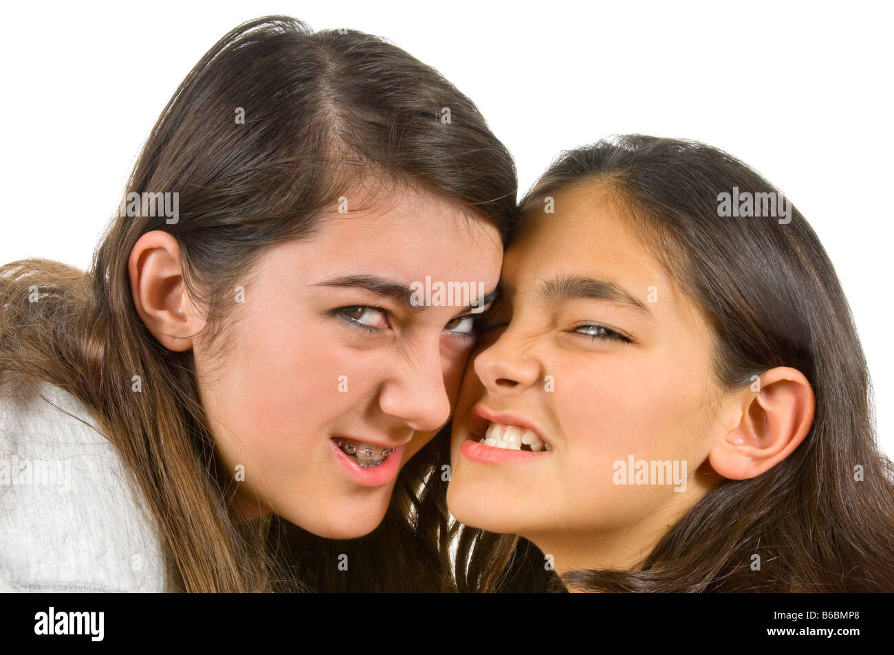 Horizontal close up portrait of two teenage sisters snarling menacingly during a fight against a white background Stock Photo