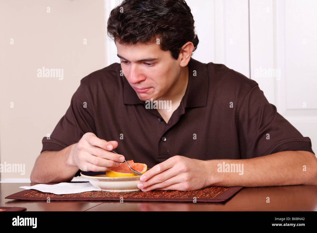 teen eating a grapefruit for breakfast Stock Photo Alamy
