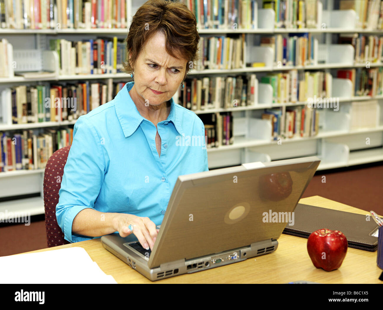 A school librarian frowns as she reviews students online activity Stock Photo