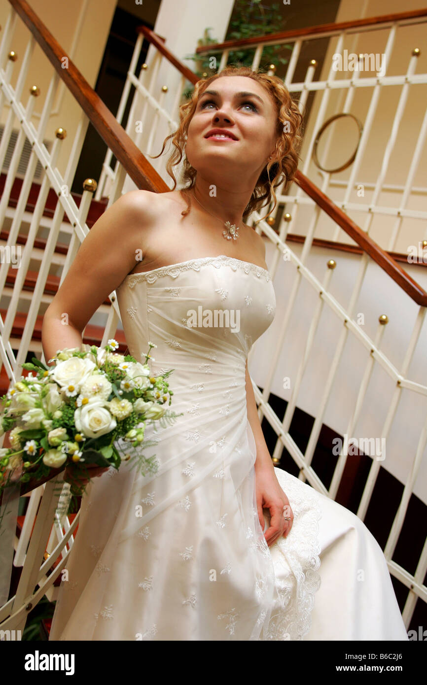 Smiling pretty bride walking downstairs with bouquet Stock Photo