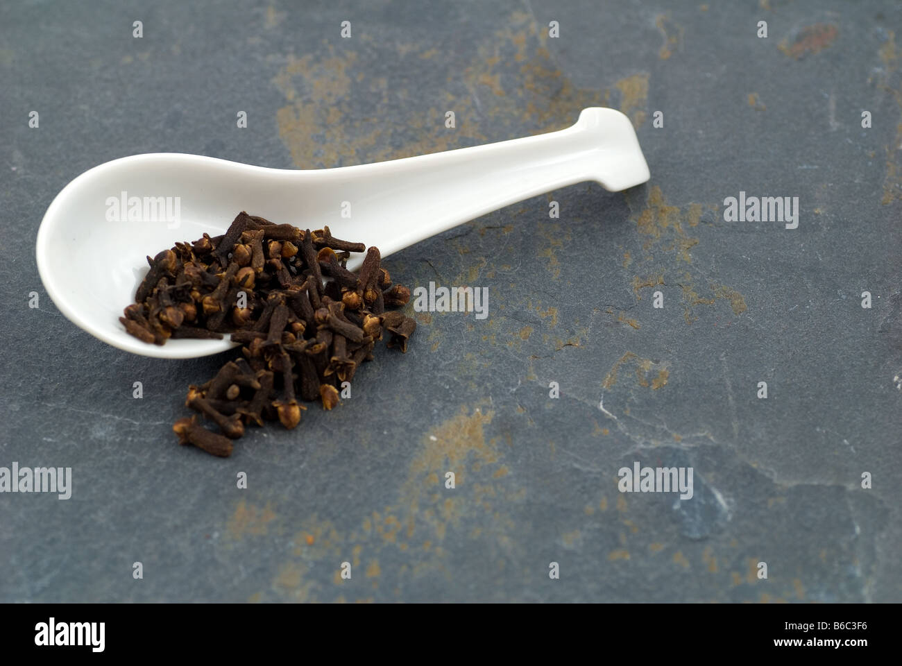 Cloves in an overturned soup spoon on slate Stock Photo Alamy