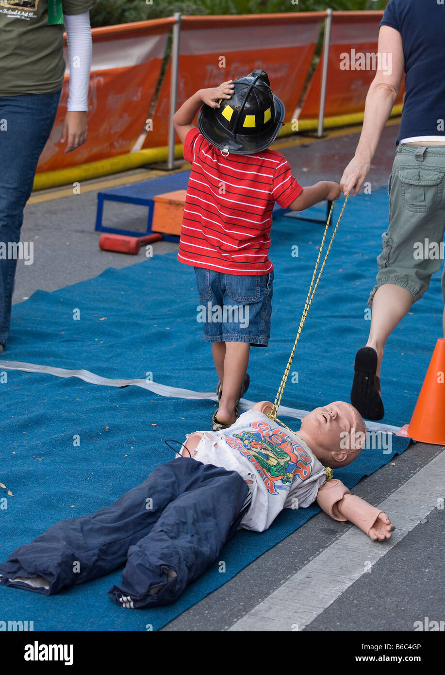 kids at fire department obstacle course with child dummies at Downtown Arts Festival Gainesville Florida Stock Photo