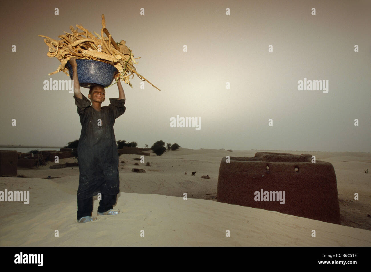 Mali, Bamba, boy carrying fuelfood on head. Stock Photo