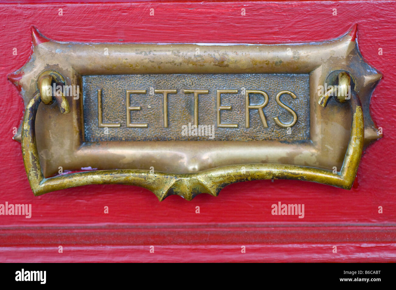An antique brass letter box in a red door Stock Photo