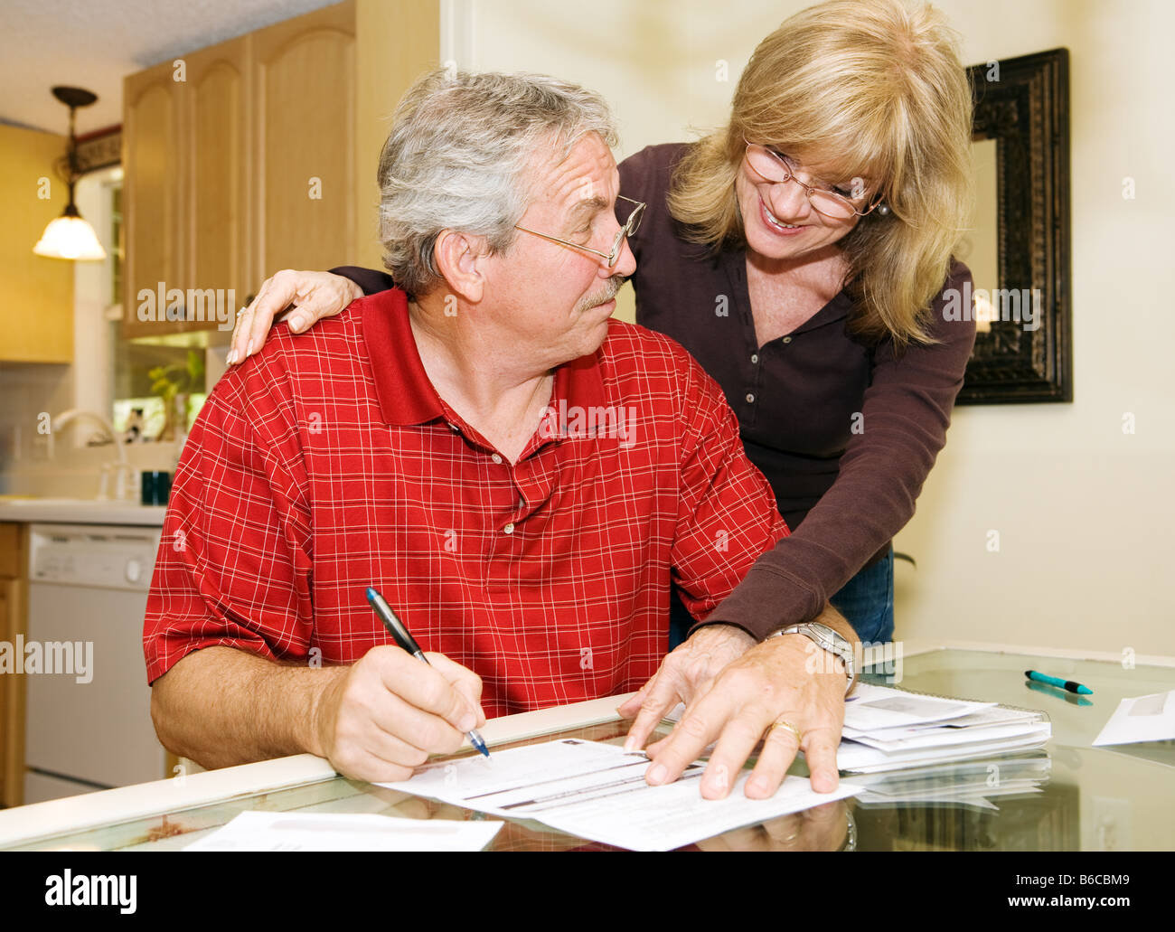 Senior woman persuading her husband to sign paperwork He looks skeptical Stock Photo