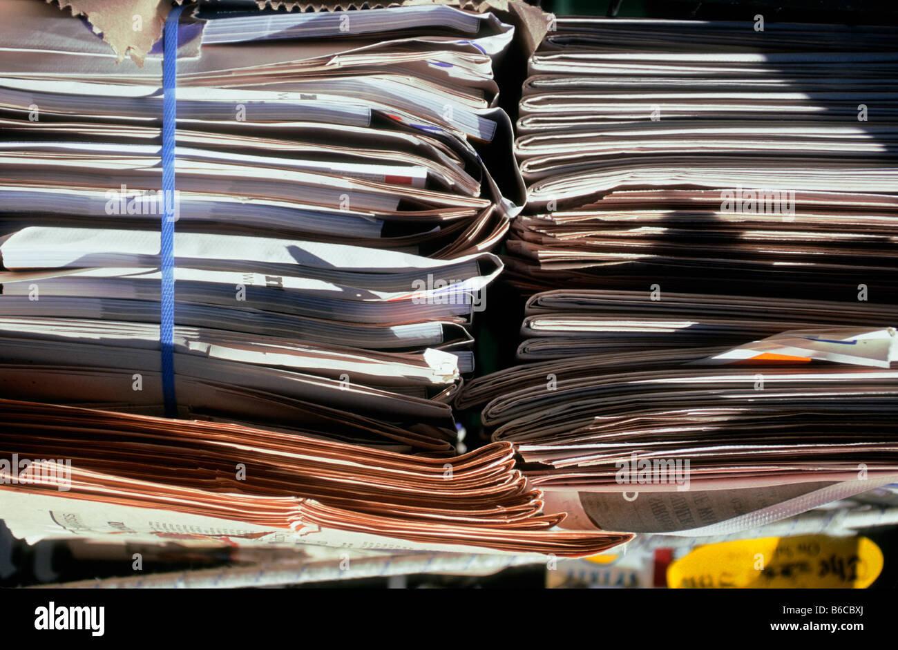 Stacks of bound newspapers tied up at newsstand waiting for pick up or delivery or recycling New York City, USA Stock Photo