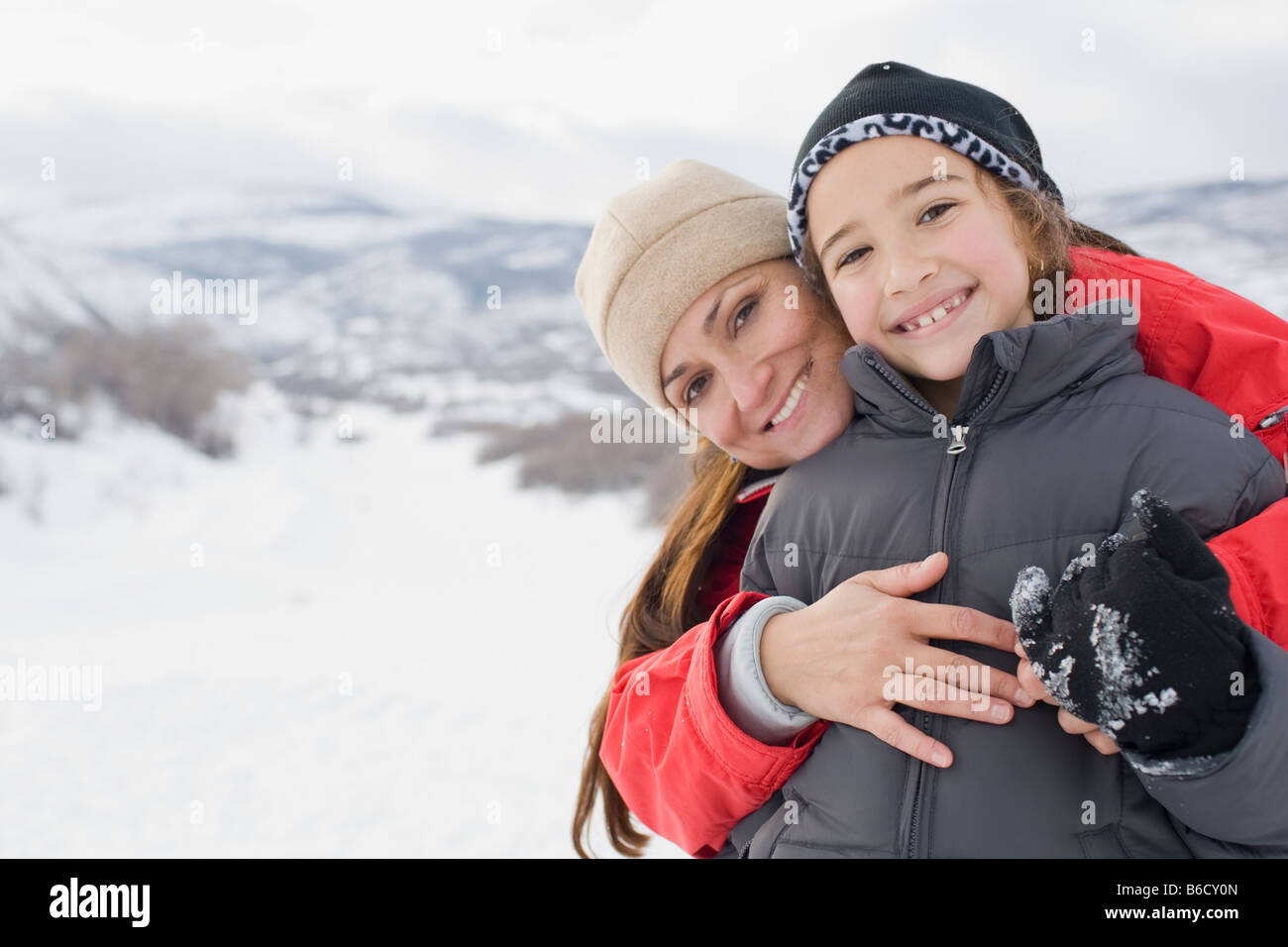 Hispanic mother hugging son in snow field Stock Photo