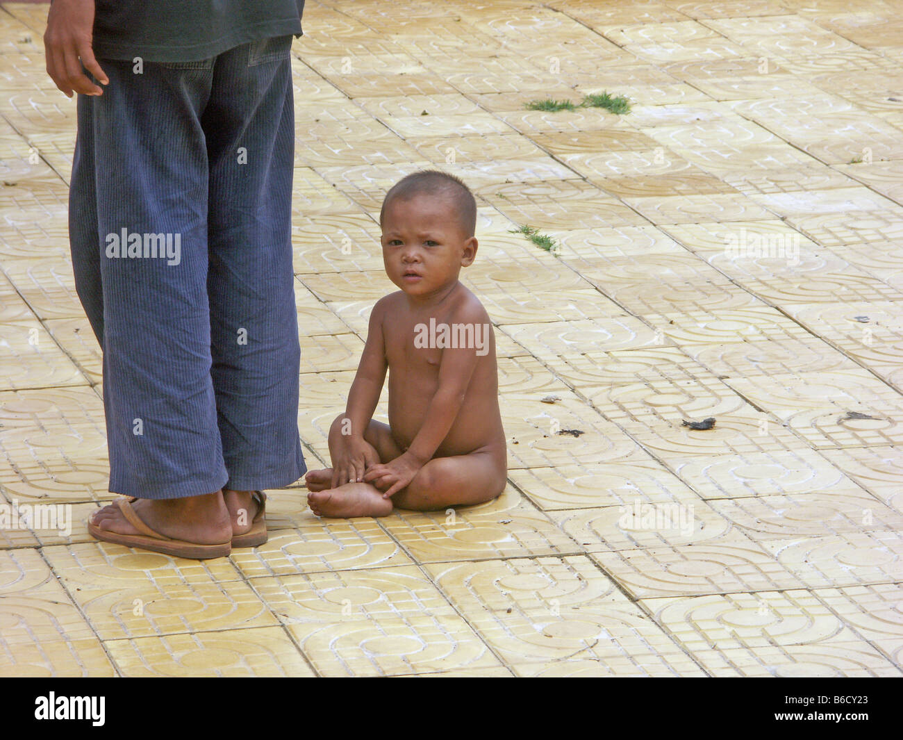 Portrait of naked boy sitting on floor besides person Stock Photo - Alamy