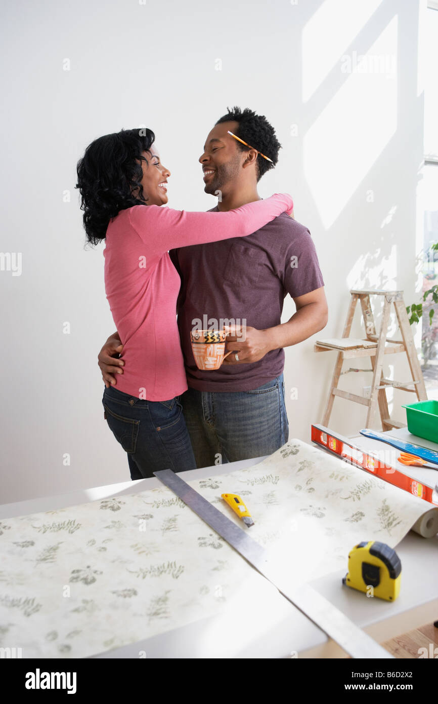 African couple measuring wallpaper and  hugging Stock Photo