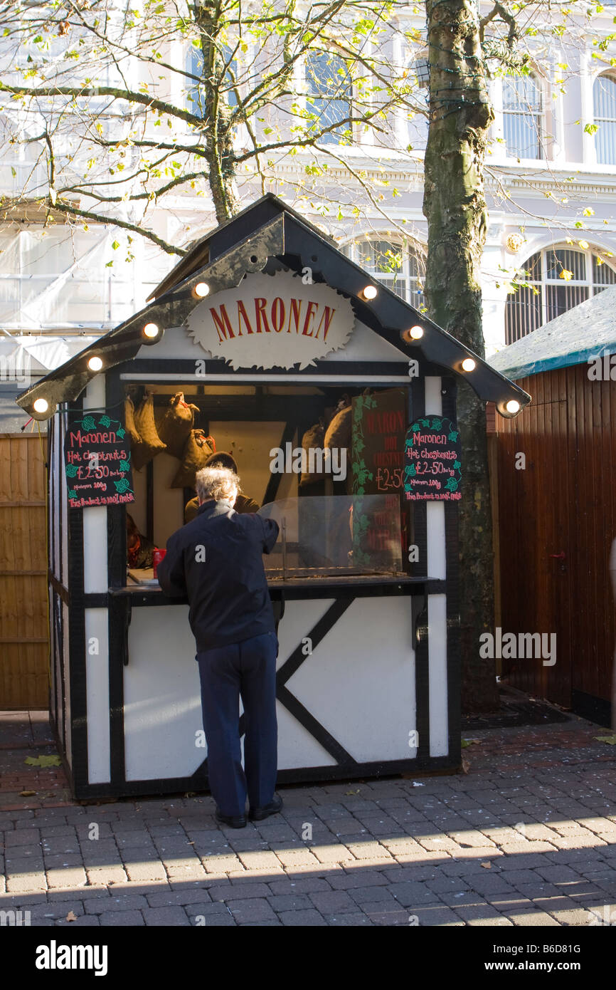Man buying chestnuts Maron Maronen from a market stall at the Manchester Christmas Xmas Market Stock Photo