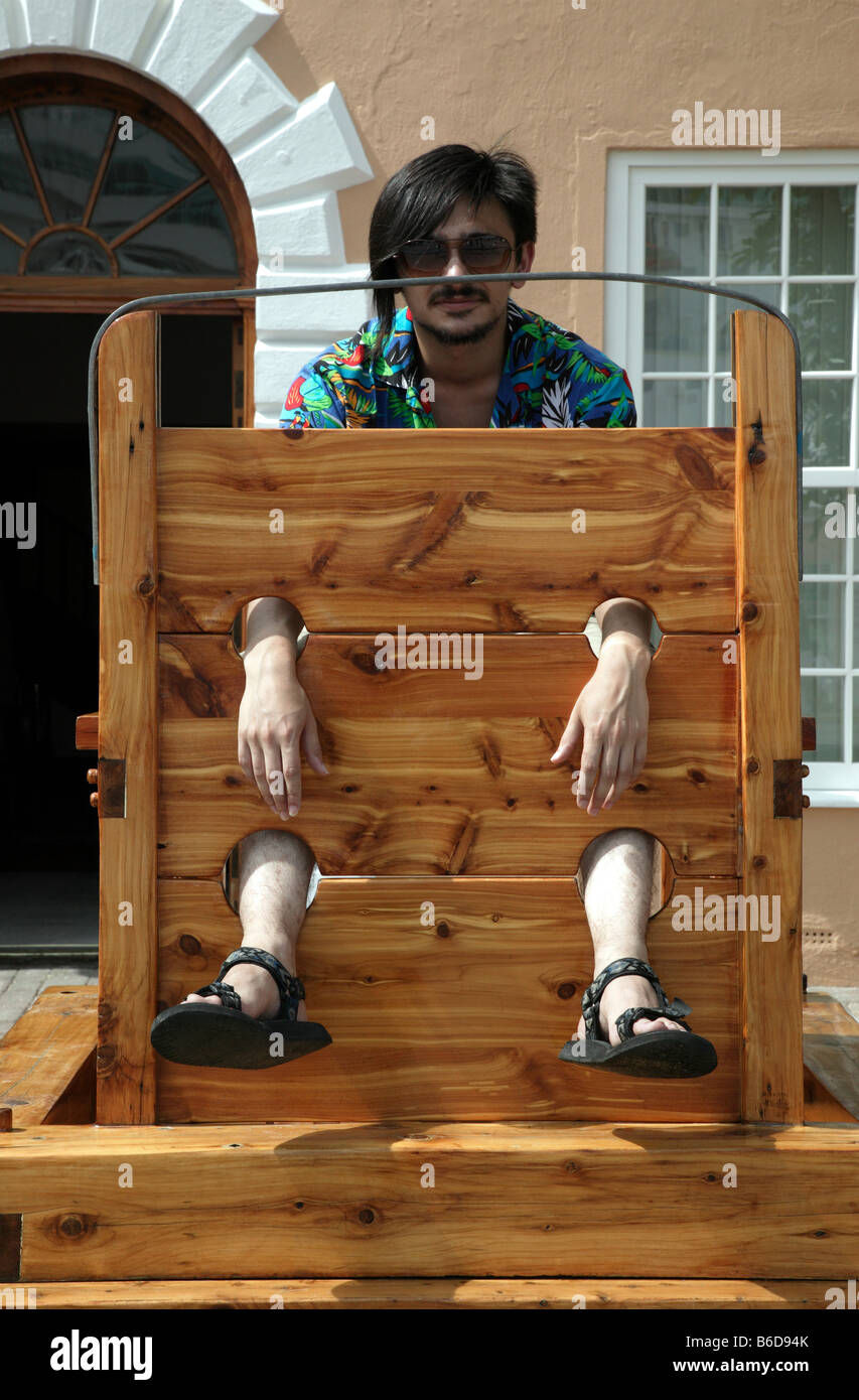 A young man poses in a replica of the Stocks in the Historic King's