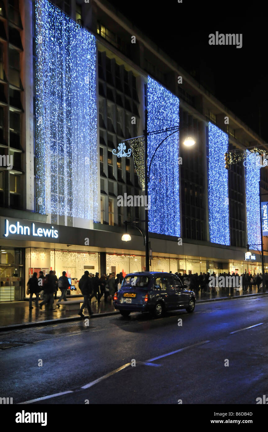 John Lewis department store shop windows in Oxford street with Christmas lights and London West End taxi black cab England UK Stock Photo