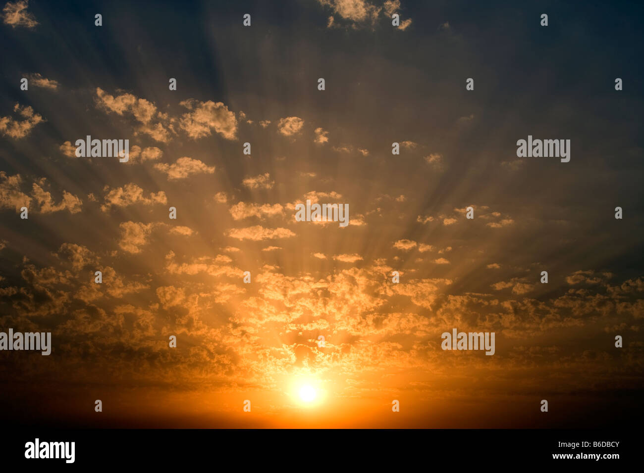 CLOUDSCAPE OF SUN LIGHT RAYS THROUGH BACKLIT PUFFY CLOUDS ON YELLOW SKY Stock Photo