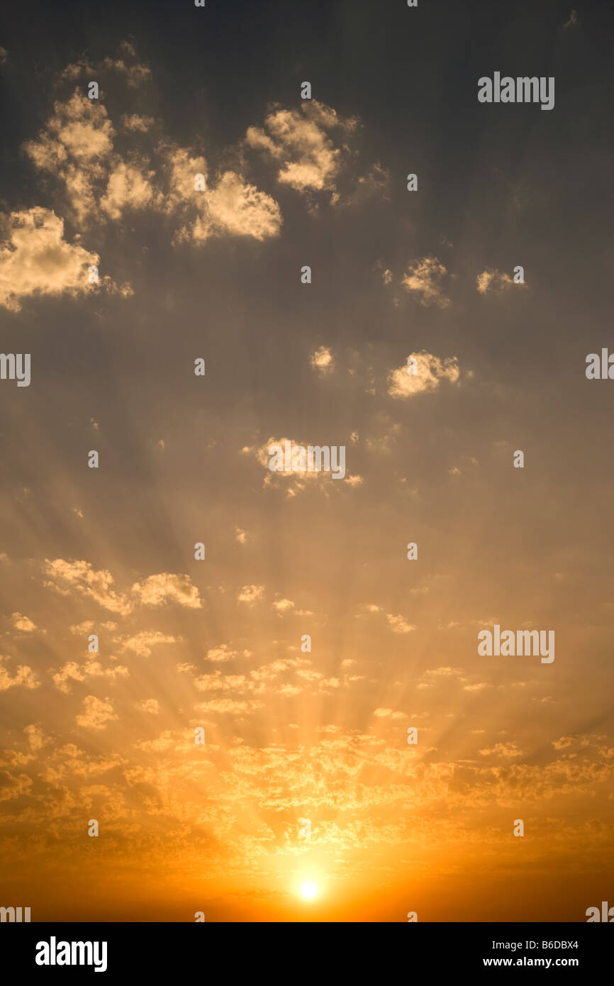 CLOUDSCAPE OF SUN LIGHT RAYS THROUGH BACKLIT PUFFY CLOUDS ON YELLOW SKY Stock Photo