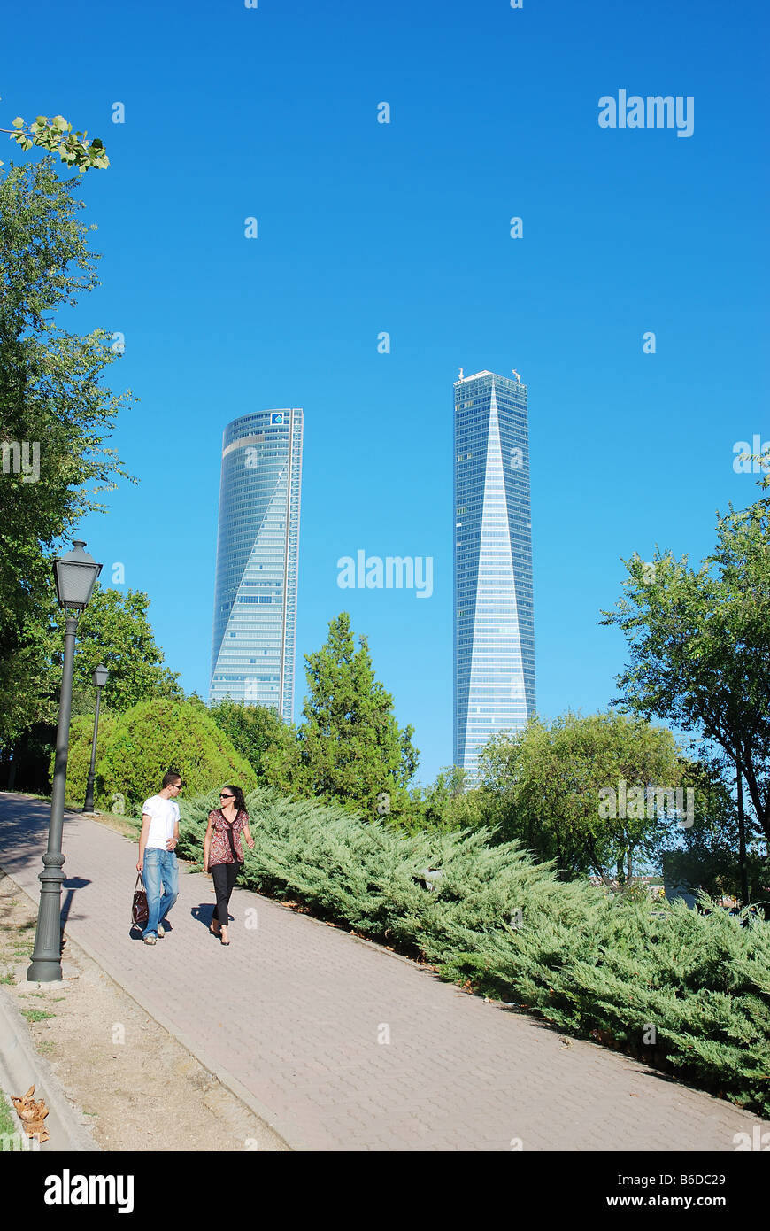 Young couple walking in the park near Tower Espacio and Tower Cristal. Madrid. Spain. Stock Photo