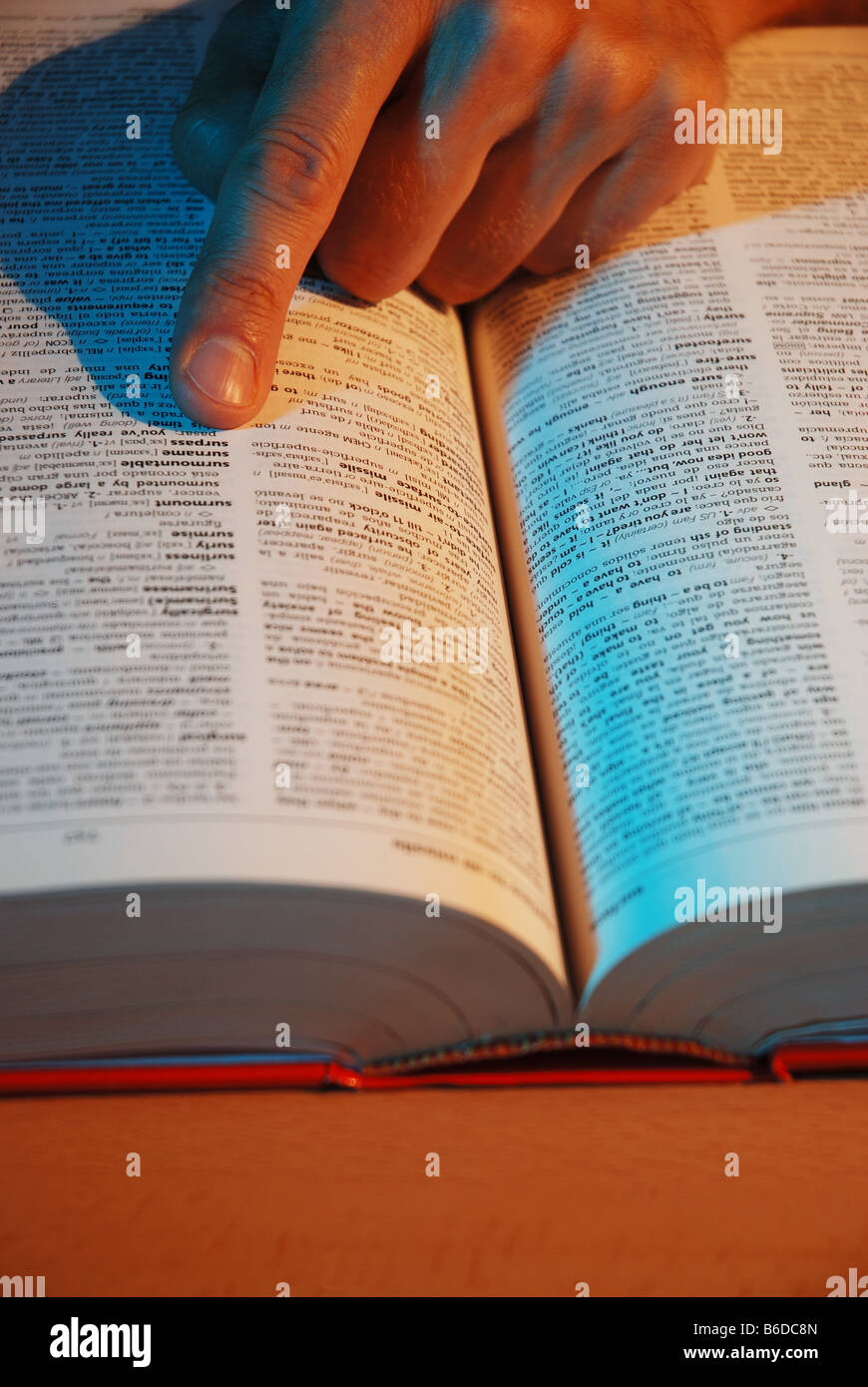 Man's index finger pointing to word in dictionary. Stock Photo