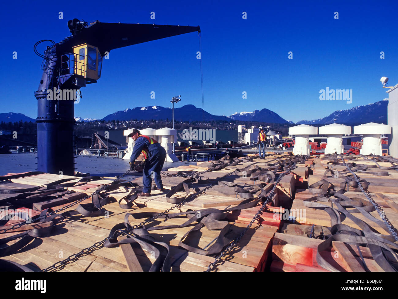 Lumber being loaded onto ship by longshoremen, shipping terminal, Port