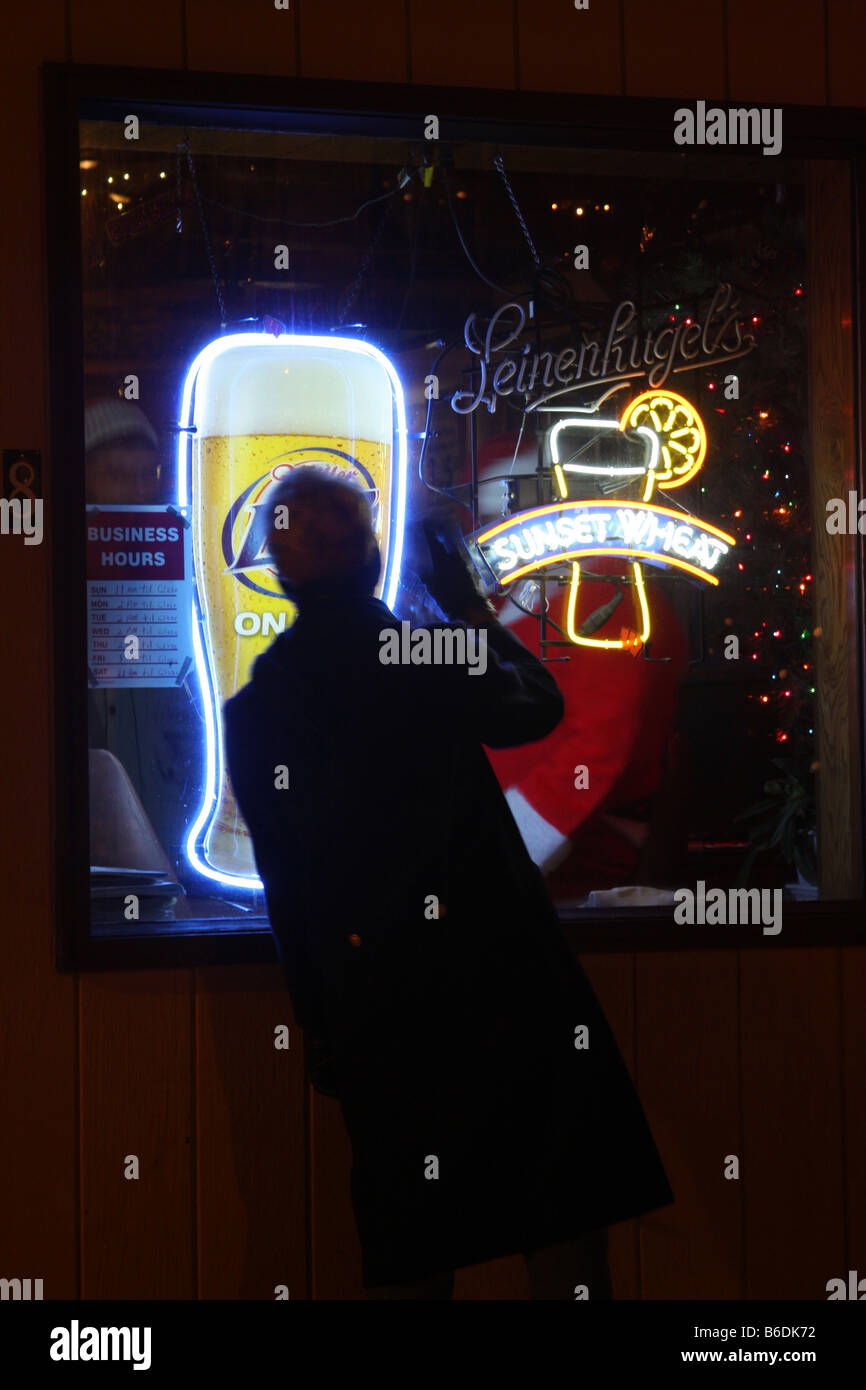 A woman waving to Santa Claus sitting in the window of a bar in Wisconsin with Leinenkugels and Miller Lite Beer signs Stock Photo