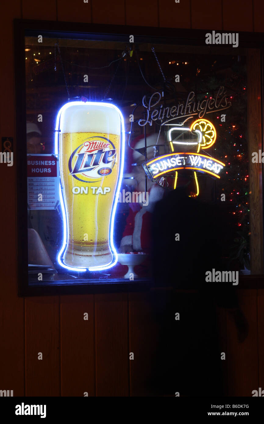 A man dressed up as Santa Claus sitting in the window of a bar with Leinenkugels and Miller Lite Beer signs in Wisconsin Stock Photo