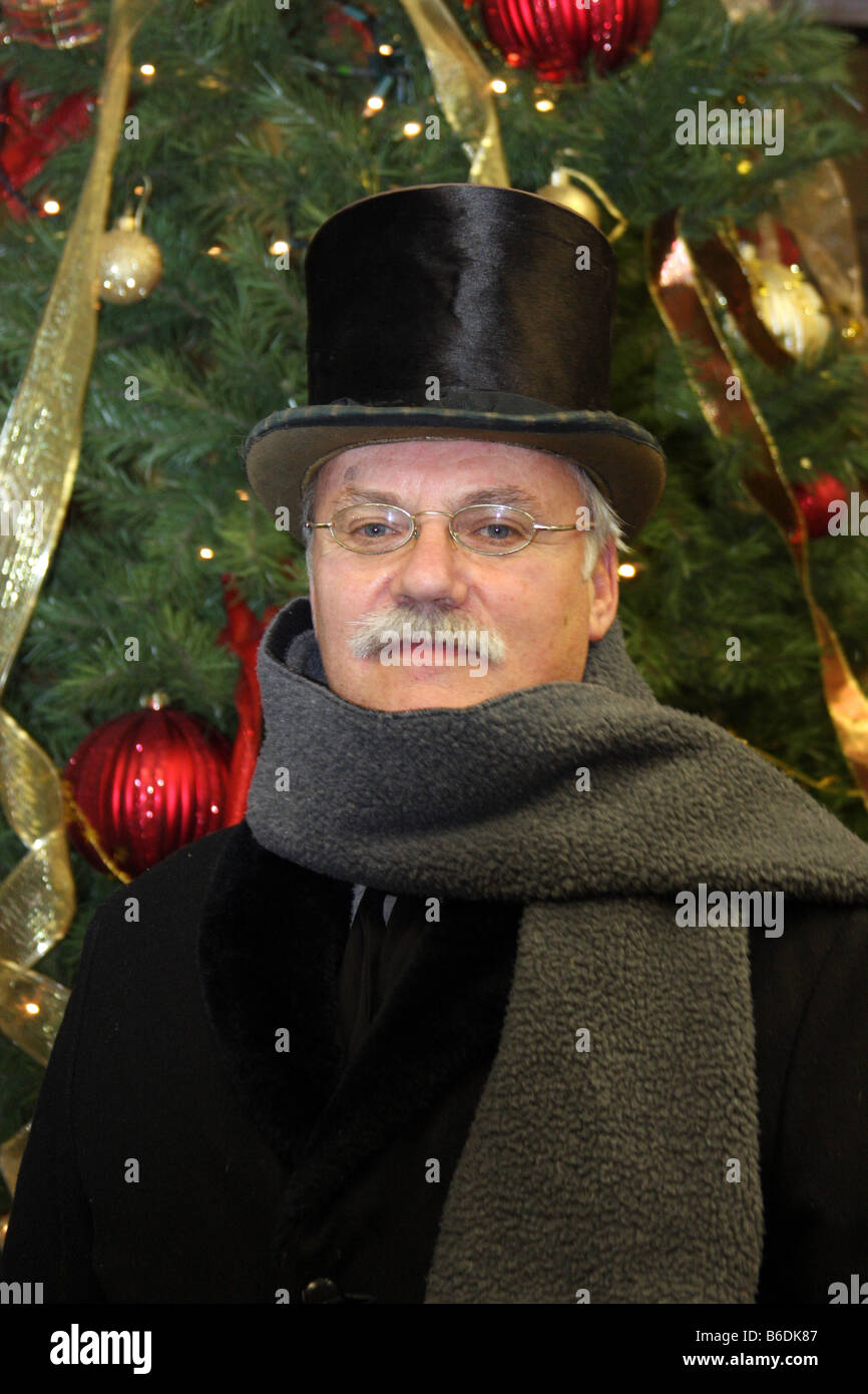 A victorian period dressed man in front of a Christmas Tree Stock Photo