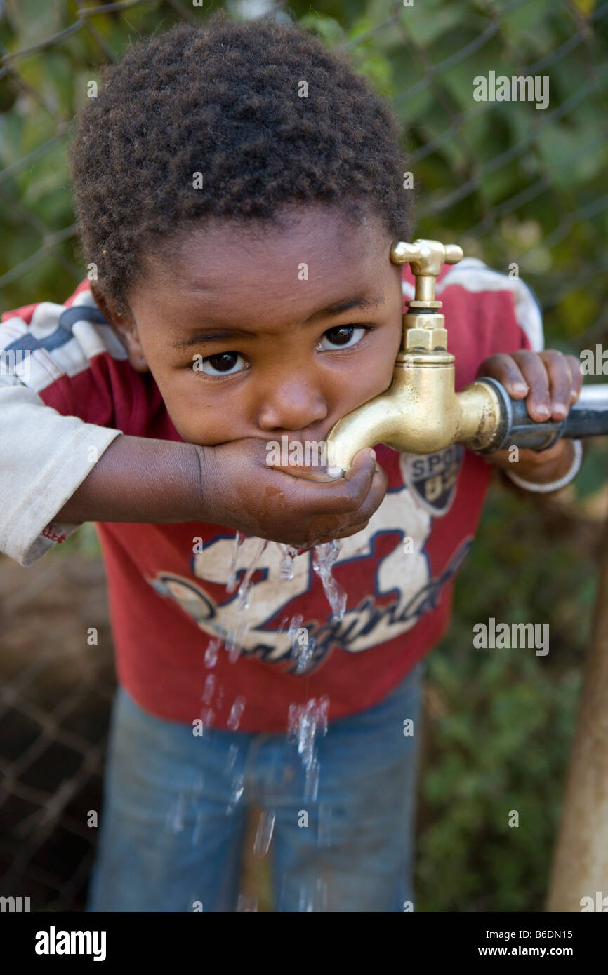 South Africa, Johannesburg, Soweto, Slums or squatter camp. Boy drinking water at tap Stock