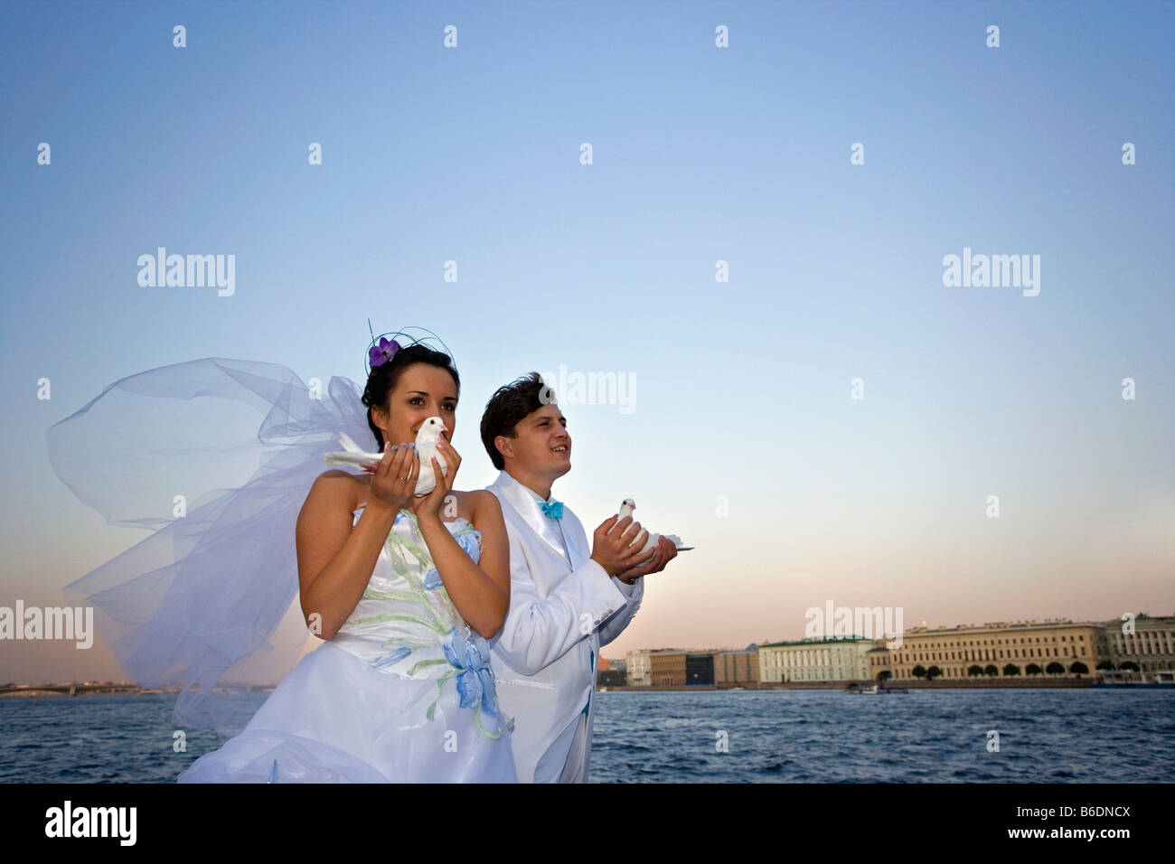 Russia, Saint Petersburg, Neva river. Hermitage background. Couple celebrate their marriage with white pigeon. Stock Photo