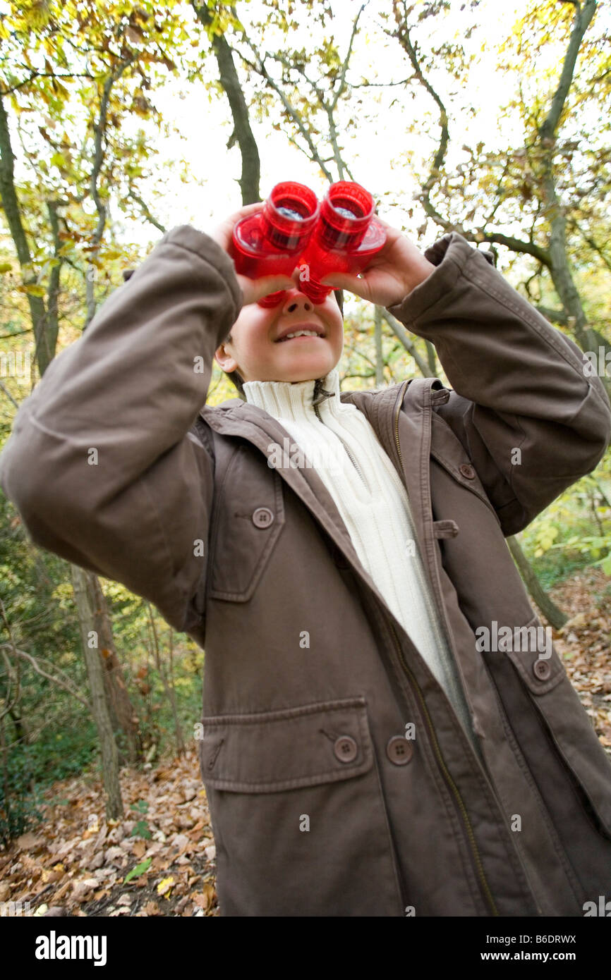 Boy using binoculars in a wood in autumn. Binoculars contain magnifying lenses that are used to