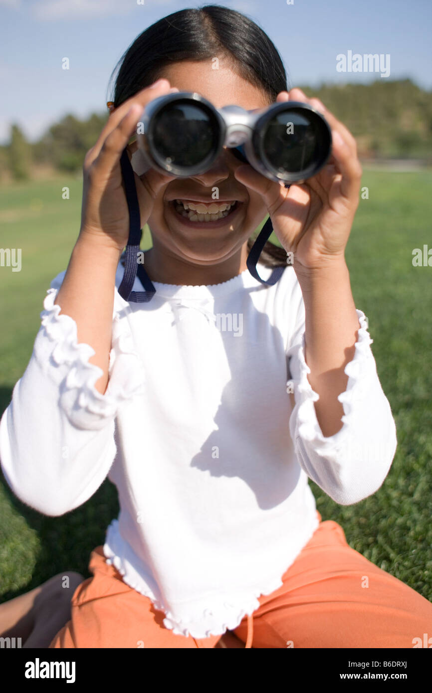 Girl using binoculars. Binoculars contain magnifying lenses that are