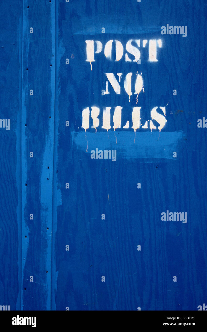 Urban Scene of words POST NO BILLS in Dripping White Paint on a Blue Wall at a Construction Site in New York City USA Copy Space Stock Photo