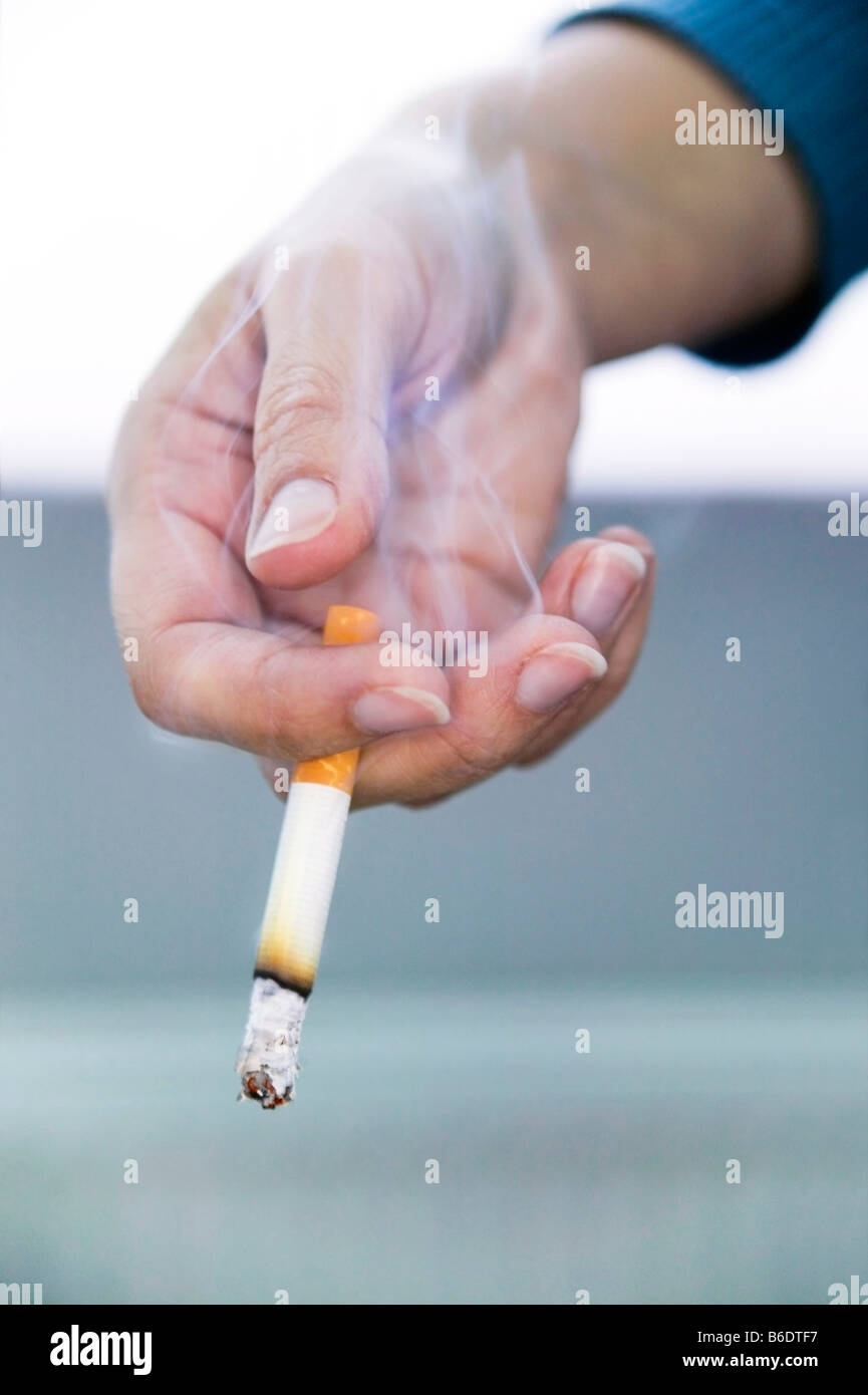 Smoking.Smoke rising from a lit cigarette in a person's hand Stock Photo