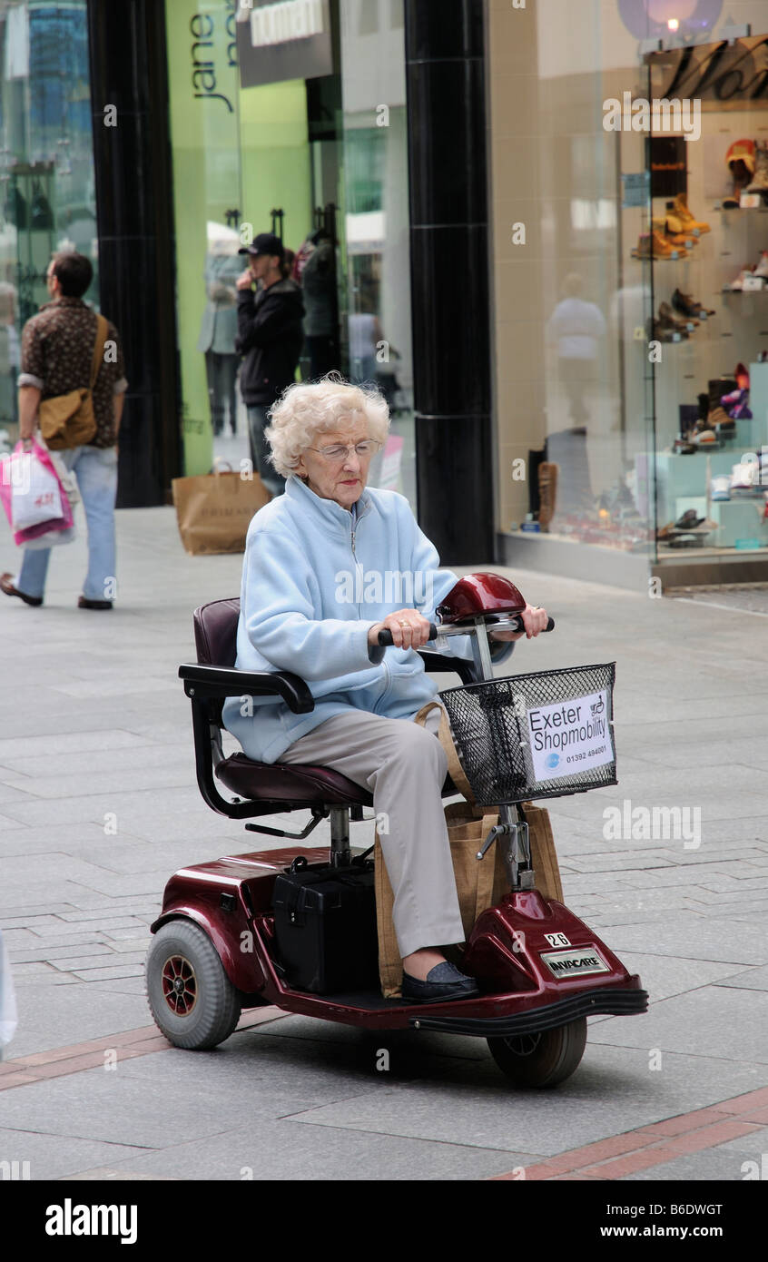 Woman riding a shopmobility scooter in Exeter shopping centre. Devon  England UK Stock Photo - Alamy