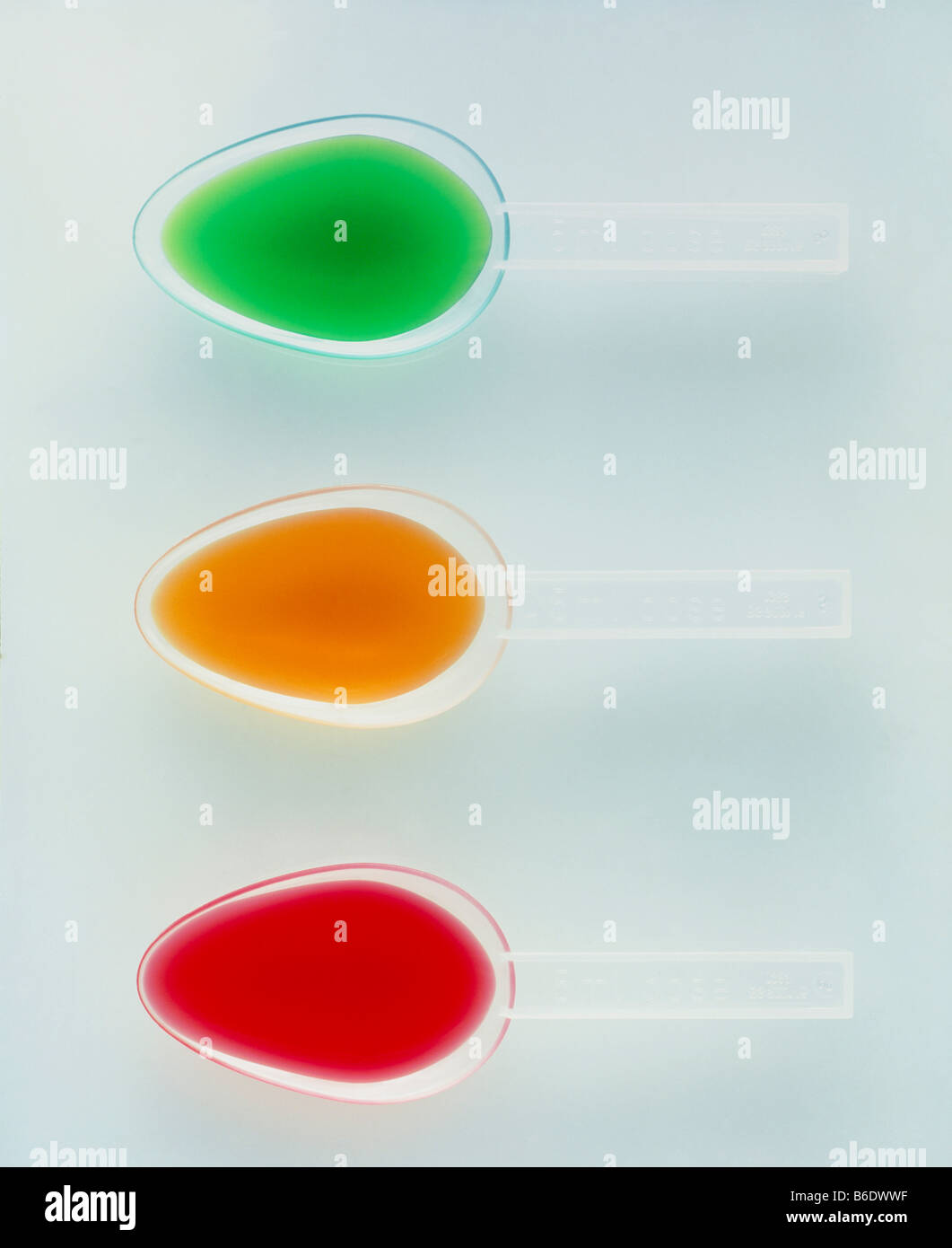 Spoonfuls of medicine. Coloured liquid medicines in three 5 millilitre spoons which help to measure the correct dose. Stock Photo