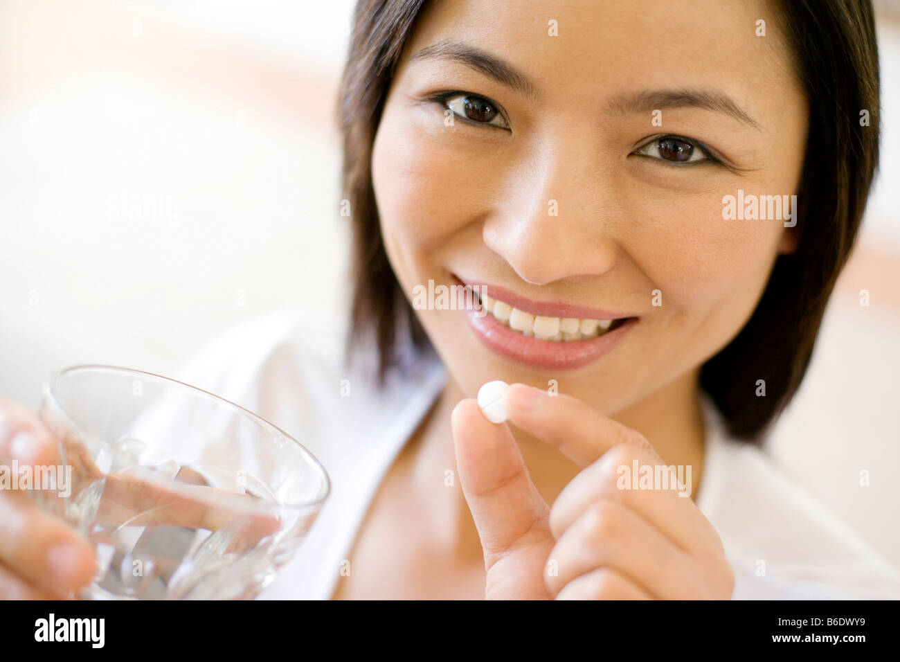Woman taking a pill with a glass of water. Stock Photo