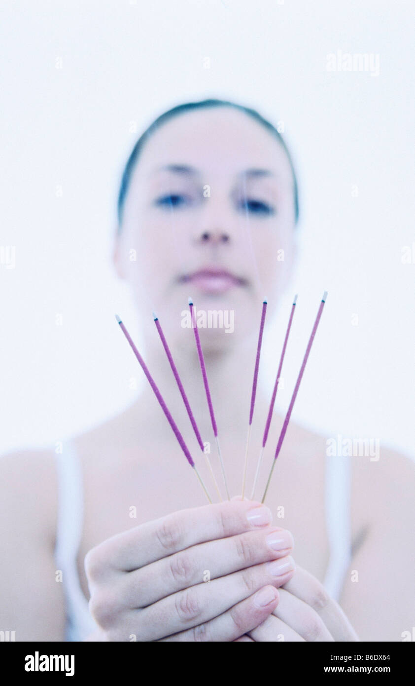 Woman holding burning incense sticks release a highly fragrant smoke